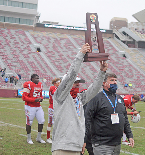 Cardinal Gibbons coach Matthew Dubuc receives the state-championship trophy from FHSAA coordinator of athletics Frank Beasley celebrate Cardinal Gibbons' 35-21 victory over Jacksonville Bolles on Thursday, Dec. 17, 2020, in the Class 4A FHSAA State Football Championship Game at Bobby Bowden Field at Doak Campbell Stadium in Tallahassee.