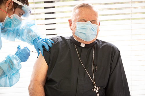 Archbishop Thomas Wenski winces as he receives a dose of the COVID-19 vaccine when Florida state public health officials rolled it out Dec. 16, 2020 at St. John's Nursing Center in Fort Lauderdale, part of Catholic Health Services of the Archdiocese of Miami. Staff and residents of the facility were offered the Pfizer-BioNTech COVID-19 vaccine, which the U.S. Food and Drug Administration authorized for emergency use Dec. 11, 2020.