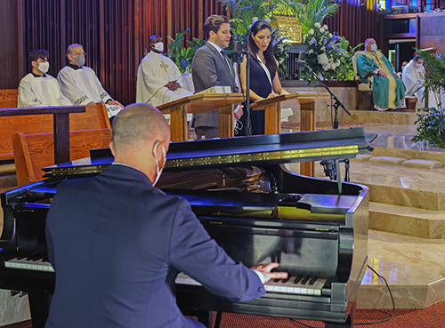 Roberto Berrocal, director musical de St. Hugh, toca el piano mientras los cantantes de ópera Martin Nuspaumer y Maria Antúnez cantan durante la Misa del 60 aniversario de la parroquia, el 15 de noviembre de 2020.