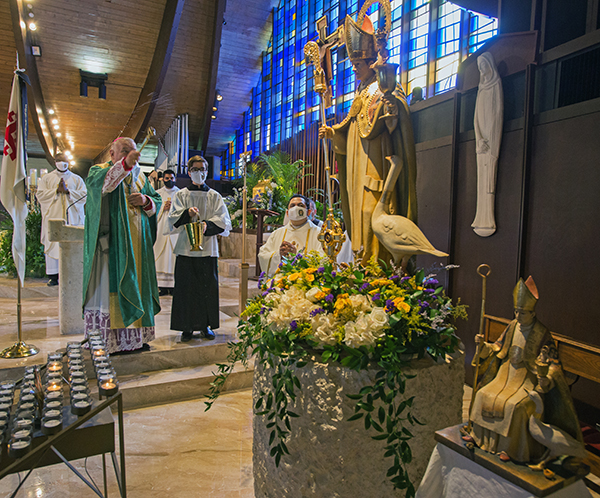 Archbishop Thomas Wenski blesses a new statue of St. Hugh during the parish's 60th anniversary Mass, Nov. 15, 2020.