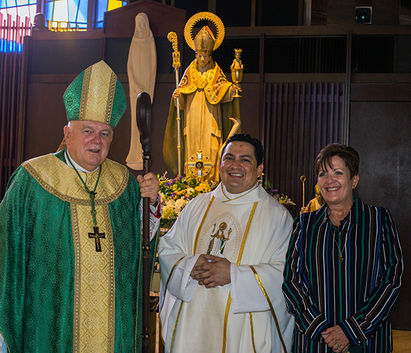 Archbishop Thomas Wenski poses with Father Luis Largaespada, St. Hugh's pastor, and Mary Fernandez, St. Hugh School's principal, in front of the new statue of the parish's patron saint, which the archbishop blessed during the 60th anniversary Mass, Nov. 15, 2020.