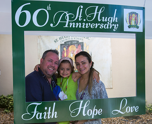 Alfonso López, su esposa Gabriella López, y su hija Isabella de 6 años, posan para una foto con el marco del 60 aniversario de St. Hugh, después de la Misa celebrada por el Arzobispo Thomas Wenski, el 15 de noviembre de 2020.