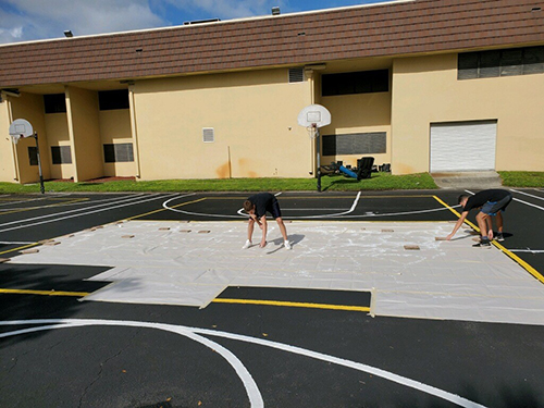 A stencil in 10-foot sections helped Columbus High senior William Dunkley, Jr., create colorful new basketball and box ball courts at the school he attended as a child, Our Lady of the Lakes in Miami Lakes.