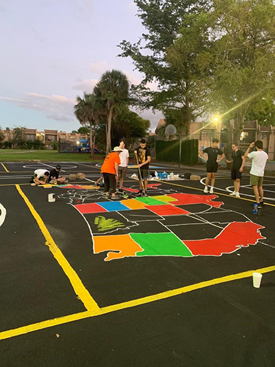 Columbus High senior William Dunkley, Jr., along with friends and their parents, works on his Eagle Scout project, creating colorful new basketball and box ball courts at Our Lady of the Lakes School in Miami Lakes.