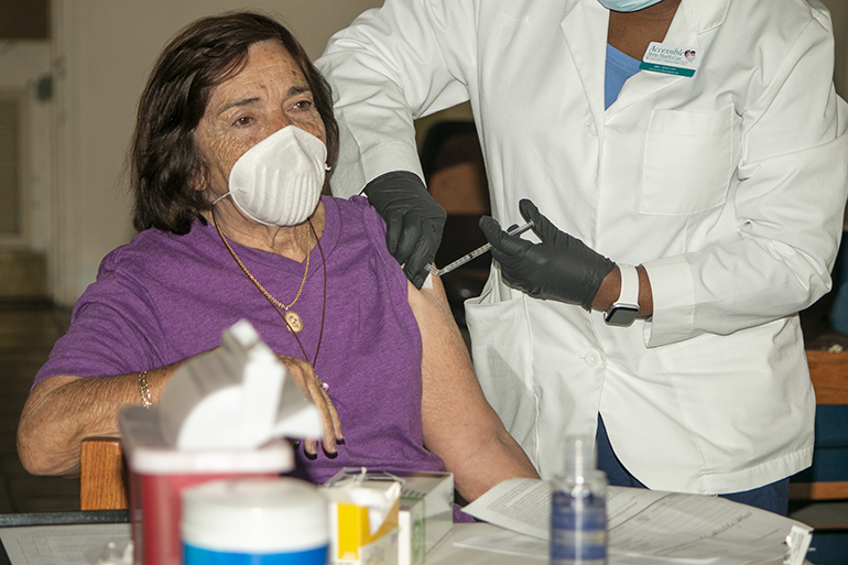 Reina Rodríguez, de 85 años, feligresa de St. John the Apostle en Hialeah, recibe su primera dosis de la vacuna contra el COVID-19 de Moderna en la iglesia San Lázaro en Hialeah, el 20 de enero de 2021. San Lázaro se convirtió en la primera parroquia arquidiocesana en servir como un sitio de vacunación contra el COVID-19. Recibieron la vacuna un total de 700 residentes de Hialeah y Hialeah Gardens de 65 años o más, incluyendo 150 feligreses de San Lázaro. La distribución, apoyada por el estado, fue organizada por el Comisionado del Condado de Miami-Dade, René García, que representa la zona.