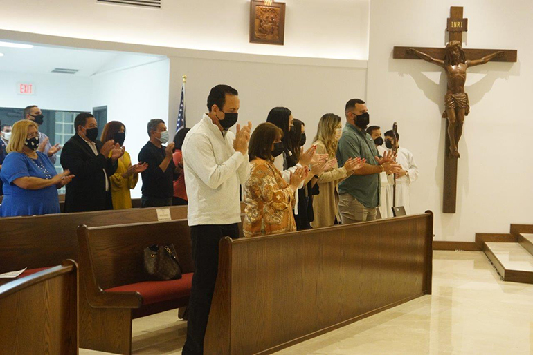 Los feligreses aplauden durante la misa donde el arzobispo Thomas Wenski consagró el nuevo altar en la Iglesia Madre de Cristo en Miami, el 1 de enero de 2021. También bendijo el espacio renovado para el culto. Visible en la parte trasera: el nuevo crucifijo,
de tamaño natural, tallado en madera así como una de las nuevas Estaciones de la Cruz talladas en madera.