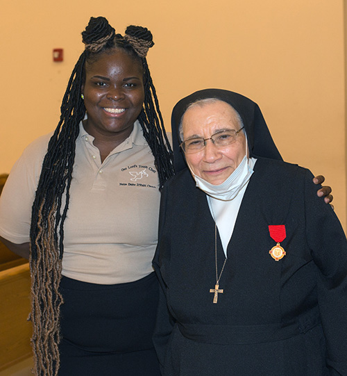 La Hna. Salesiana Yamile Saieh posa con Jessica Cola, de 28 años, una exalumna de la Hna. Yamile cuando enseñaba educación religiosa a adolescentes en Notre Dame d'Haiti en Miami. Cola es ahora la cantante principal del coro de jóvenes de Notre Dame d'Haiti y cantó "Draw Me Close To You" durante la Misa de despedida de la Hna. Yamile, celebrada el 15 de septiembre de 2020 en Notre Dame.