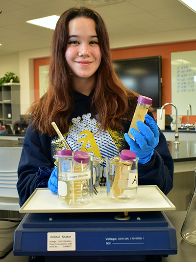 Kaitlyn Urruela shows some of the equipment she used in a science project at St. Thomas Aquinas High School to explore how microbes might be used to break down waste plastic.