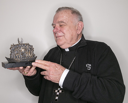 Archbishop Thomas Wenski holds a miniature replica of the Angels Unawares sculpture by Canadian artist Timothy Schmalz. A full-size replica of the immigration-themed artwork will be on display in Miami beginning Feb. 9, 2021.