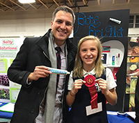 Dentist and mentor Steve Altman stopped by Nikita Marino's booth at her school science fair in Greenwich Catholic School in Connecticut, where she received second place for her invention of Bite Bright.