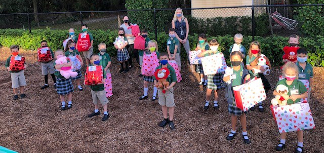 First grade students at Mary Help of Christians School pose with their teachers, Alice Smith and Janet Cefali, while holding the goody bags they filled with items for Kids in Distress of Broward, which were delivered just before Valentine's Day 2021.