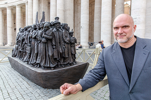 Canadian sculptor Timothy P. Schmalz poses next to his sculpture on the theme of refugees and migration titled 'Angels Unawares' in St. Peter's Square, Oct. 1, 2019.