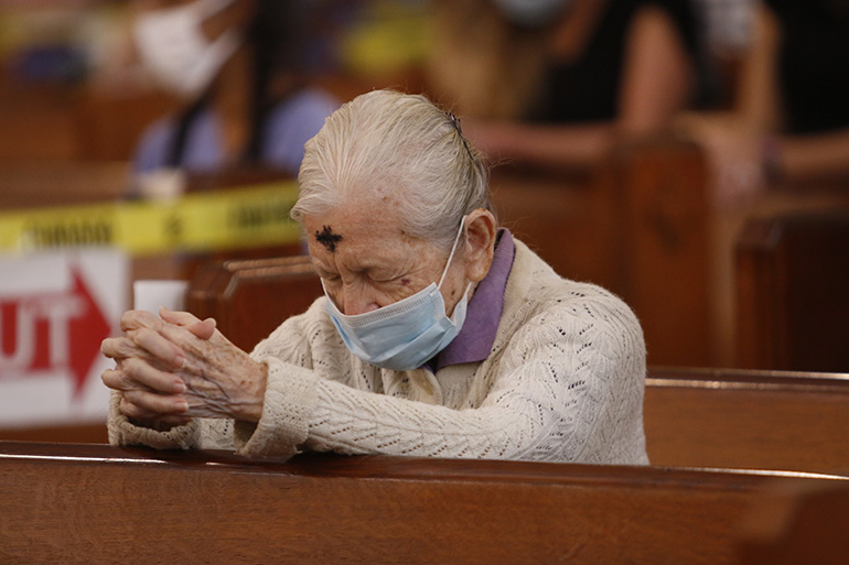 A woman prays during the Ash Wednesday Mass celebrated by Archbishop Thomas Wenski at Miami's historic Gesu Church, Feb. 17, 2021.