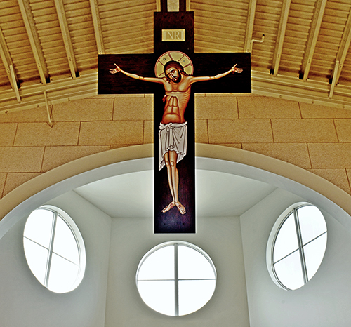 Above the chancel, a full-size crucifixion icon hangs at an angle, making it visible even to those sitting in the front.