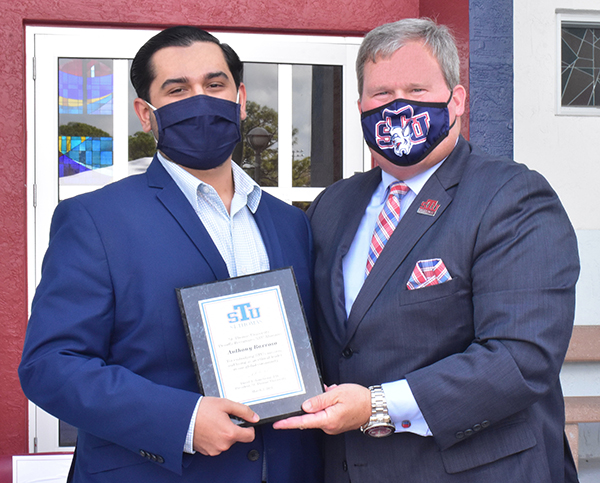 Anthony Barroso, left, gets a plaque from President David Armstrong of St. Thomas University for his action against an anti-Semitic graffito. The presentation took place March 2, 2021.