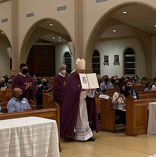 Archbishop Thomas Wenski processes down the aisle of St. Mary Cathedral with the Book of the Elect, where catechumens have signed their names, during one of four Rite of Election ceremonies that took place in the Archdiocese of Miami on the First Sunday of Lent, Feb. 21, 2021. COVID protocols resulted in added ceremonies to accommodate everyone with social distancing.