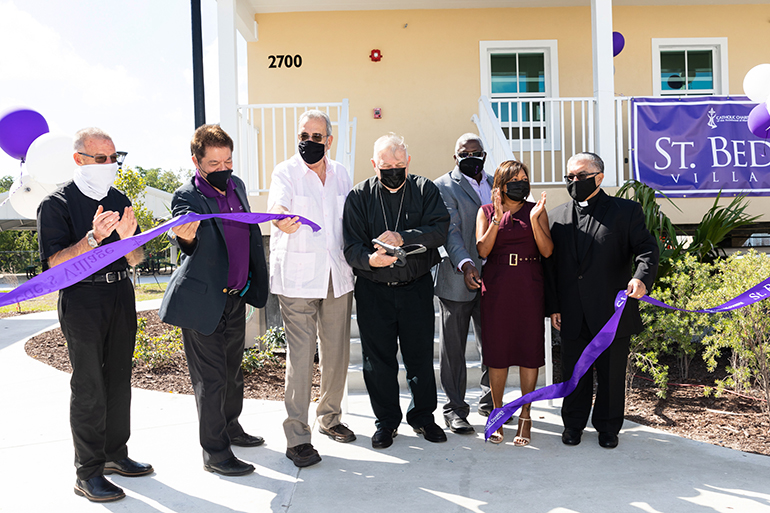 Archbishop Thomas Wenski cuts the ribbon for Catholic Charities-sponsored St. Bede's Village in Key West March 5, 2021. Along with him, from left, are Father John Baker, pastor of the Basilica of St. Mary, Star of the Sea Parish in Key West; Miami Catholic Charities CEO Peter Routsis-Arroyo; Orestes Wrves, a member of the Catholic Charities board of directors; Jules Jones, CFO of Catholic Charities; Devika Austin, chief administrative officer for Catholic Charities; and Msgr. Roberto Garza, board chairman for Catholic Charities.