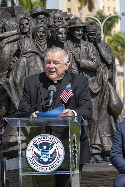 Archbishop Thomas Wenski delivers the keynote address after 10 people took the oath of U.S. citizenship in a ceremony held in the shadow of the Angels Unawares sculpture and Miami's Freedom Tower, March 24, 2021.
The Archdiocese of Miami partnered with U.S. Citizenship and Immigration Services to hold the naturalization ceremony on the corner of Bayfront Park where the sculpture has been on display since Feb. 9, 2021. It will be moved to its next city, New Orleans, on April 8, 2021.