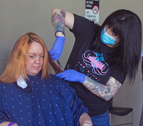 Hair stylist Daniella Lopez, of The Miami Give Back, cuts client Destiny Bruno's hair during Fit 'n Trim day, March 24, 2021 at Camillus House.
