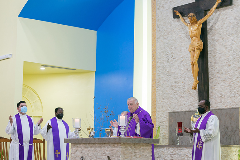 Archbishop Thomas Wenski presides at the Mass marking Catholic Charities' 90th anniversary, which was celebrated at St. Joachim Church in Miami March 26, 2021. Concelebrating, from left, are Father Pedro Torres, parochial vicar at St. Joachim; Spiritan Father Alexander Ekechukwu, pastor of Holy Redeemer Church in Liberty City; and Father Reginald Jean-Mary, administrator of Notre Dame d'Haiti Mission in Miami, far right. Also concelebrating but hidden in the photo is Msgr. Roberto Garza, pastor of St. Joachim and chair of Catholic Charities' board of directors.