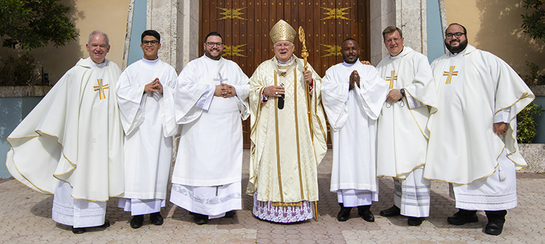 The new transitional deacons and some of the attending priests stand outside the Cathedral of St. Mary. From left, Father Alfredo Hernandez, rector of St. Vincent de Paul Regional Seminary in Boynton Beach; Deacon Agustin Estrada, Deacon Sebastian Grisales, Archbishop Thomas Wenski, Deacon Cesar Betancourt, Father Emanuele De Nigris, rector of Redemptoris Mater Archdiocesan Missionary Seminary in Hialeah, and Father Matthew Gomez, archdiocesan director of Vocations.