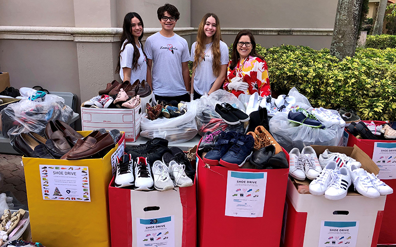 The Inguanzo siblings, Susanna, Sophia and Christopher, pose with Camillus House CEO Hilda Fernandez while sorting, cleaning and packing the 5,000 pairs of donated shoes, March 20, 2021.