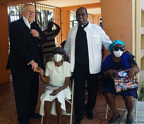 Archbishop Thomas Wenski poses with Father Reginald Jean-Mary, administrator of Notre Dame d'Haiti Mission in Miami, which hosted a vaccination event April 14, 2021. With them are Father Jean-Mary's 92-year old mother and his sister, who also waited their turn to receive the vaccine.