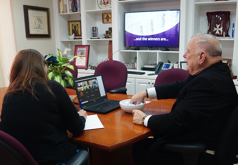 Katie Blanco Bourdeau, cabinet secretary of Stewardship and Development for the archdiocese, takes notes as Archbishop Thomas Wenski picks the winners of the "stretch goal" raffle from among the parishes that collected more than their "stretch goal" in the 2020 ABCD campaign.