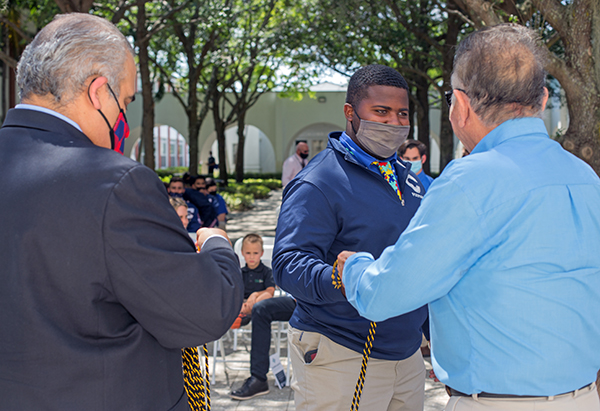 Juan Vila, left, academic dean at Christopher Columbus High School, and alumnus and benefactor Michael Carricarte, Sr., give a cord of distinction to business student Jared Trapp during the April 15, 2021 event marking the naming of the Carricarte Business, Leadership and Entrepreneurship career pathway at the all-boys Miami high school.