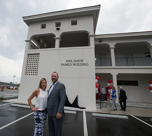 Shaun Smith-Myers, Cardinal Gibbons class of '89, and Charlie Myers pose in front of the Phil Smith Family Building after the name was unveiled, April 21, 2021.