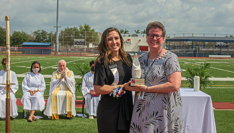 Judith Mucheck, right, head of school at Chaminade-Madonna College Preparatory, presents Samantha Stokesberry, '09, with the Founders' Award after the Mass marking the Hollywood school's 60th anniversary. The Mass was celebrated April 25, 2021 on the school's Vince Zappone Field.