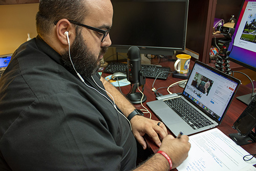 El P. Matthew Gómez, director arquidiocesano de Vocaciones, toma notas mientras el Arzobispo Thomas Wenski habla a los alumnos de sexto grado de las escuelas arquidiocesanas, durante la versión virtual de Focus 11, celebrada el 5 de mayo de 2021. El objetivo de Focus 11 es ayudar a los jóvenes a considerar su vocación en general, y la vocación al sacerdocio o a la vida religiosa en particular. El evento se celebró virtualmente este año debido a la pandemia del COVID-19.