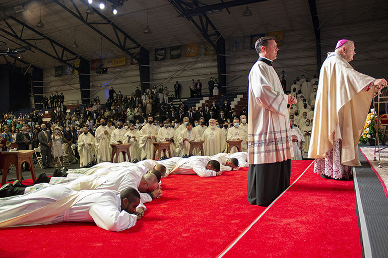 The soon-to-be-ordained priests lie prostrate on the sanctuary as Archbishop Thomas Wenski and the congregation pray the Litany of the Saints. The archbishop ordained eight new priests for the Archdiocese of Miami in a moving ceremony May 8, 2021. The ordination took place at St. Thomas University's Fernandez Family Center in order to accommodate the nearly 800 in attendance while adhering to pandemic safety protocols.