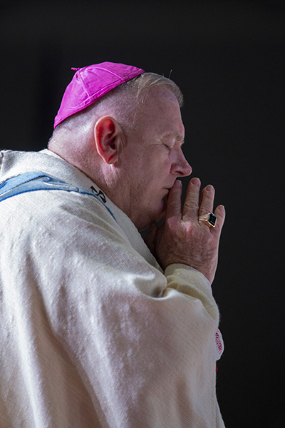 Archbishop Thomas Wenski prays during the Litany of the Saints, before ordaining eight new priests for the Archdiocese of Miami in a moving ceremony May 8, 2021. The ordination took place at St. Thomas University's Fernandez Family Center in order to accommodate the nearly 800 in attendance while adhering to pandemic safety protocols.