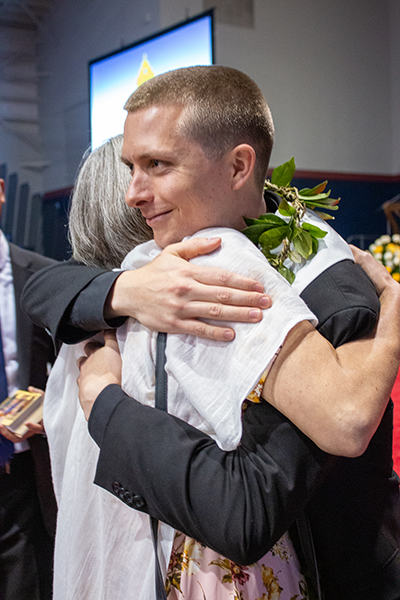 Wearing a Hawaiian style lei, newly ordained Father Paul Pierce hugs his mother, Rachel Hope, after the ceremony.