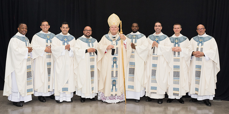 Newly ordained priests take the official photo. From left: Father Franklin Ekezie, Father Nicholas Toledo, Father Hans Chamorro, Father Alberto Chavez, Archbishop Thomas Wenski, Father Jeremy Lully, Father Leandro Siqueira, Father Paul Pierce, and Father Yosbany Alfonso.