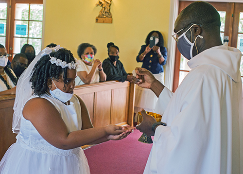 Spiritan Father Fidelis Nwankwo, administrator of St. Philip Neri Parish, gives first Holy Communion to Gabriella Williams, 9, during Mass on Trinity Sunday, May 30, 2021.