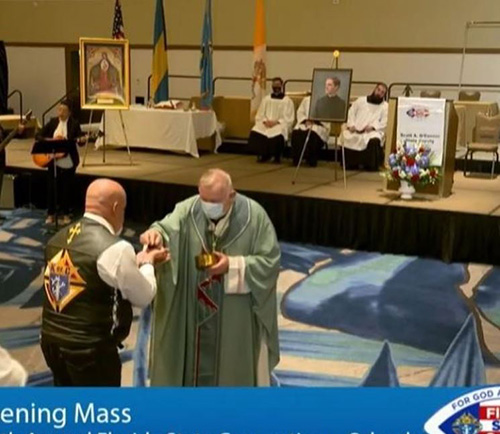 Archbishop Thomas Wenski distributes Communion while celebrating the opening Mass, May 28, 2021, at the state convention of Knights of Columbus in Orlando. The day before, he joined almost 30 Knights on Bikes on a ride from Weston to Kississime to promote vocations on the way to the convention.