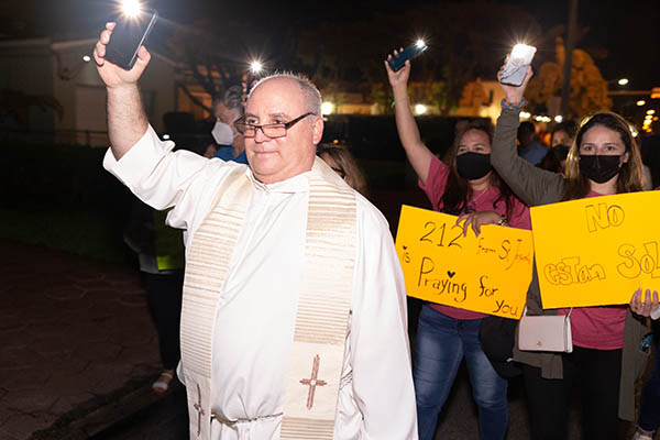 Father Juan Rumin Dominguez, parochial vicar at St. Joseph  Parish in Miami Beach, walks with the parish youth ministry groups who hosted a eucharistic prayer and candlelight vigil June 26, 2021, including a walk through the neighborhood and close to the site of the Champlain Towers South partial collapse.