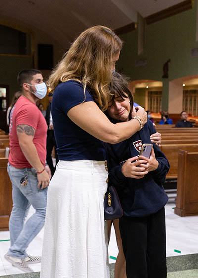A woman consoles a child at St. Joseph Parish in Miami Beach  during the eucharistic prayer and candlelight vigil hosted by the parish youth groups June 26, 2021. The evening included a walk through the neighborhood and close to the site of the Champlain Towers South partial collapse.