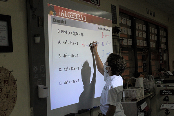 En la escuela Our Lady of the Lakes, un estudiante resuelve un problema de matemáticas en la pizarra inteligente de su clase. Al mismo tiempo, algunos de sus compañeros participaron en la lección de forma virtual y en tiempo real a través de Zoom. En todas las escuelas de la Arquidiócesis de Miami, los estudiantes tenían la opción de regresar en persona o virtualmente durante el año académico 2020-2021.