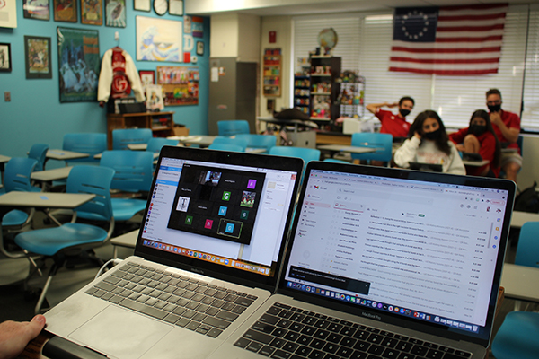 A small class at Cardinal Gibbons High is shown preparing for history class to begin May 25, 2021. Online students are shown checking into class on the computer screens, joining the hybrid classroom.