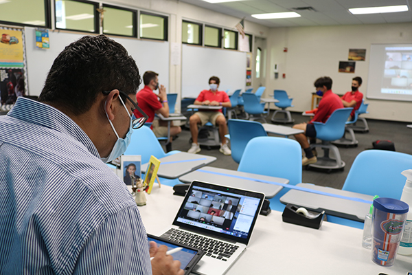 Nelson Araque multitasks and stays constantly busy during his theology class at Cardinal Gibbons High School as he teaches his online and in-person students and tries to keep them engaged and interested.