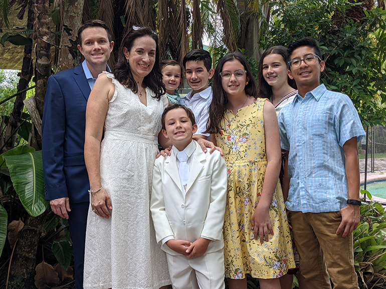 Richard Lopez gathers his family after Mass May 15, 2021 at the Church of the Little Flower in Coral Gables where his son, Nicholas, 8, received the sacrament of holy Communion. Shown standing by him is his wife Angelique and the rest of their children.