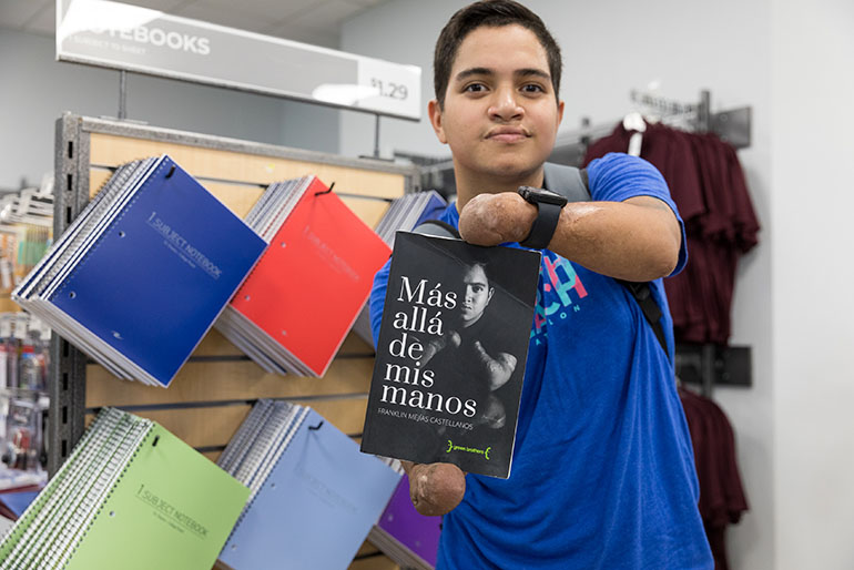 El estudiante Franklin Mejías Castellano, de St. Thomas University, que quedó físicamente incapacitado por una infección adquirida durante un viaje a La Florida desde su natal Venezuela cuando tenia 12 años, sostiene una copia de su libro, que cuenta la historia de su superación después de la pérdida de sus extremidades como consecuencia de la infección.