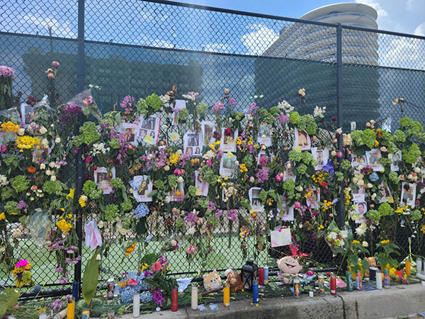 The memorial wall at the tennis court across the Champlain Towers South building collapse is filled with photos of the missing and victims, flowers, candles, rosaries, and more. Some of the toys and stuffed animals placed at the memorial were reportedly recovered from the building collapse site.