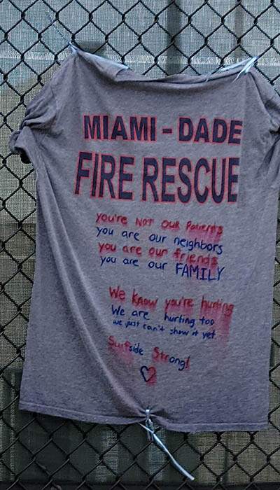 A T-shirt supporting Miami-Dade Fire Rescue and other first responders is left on the memorial wall for those affected by the Champlain Towers South building collapse in Surfside.