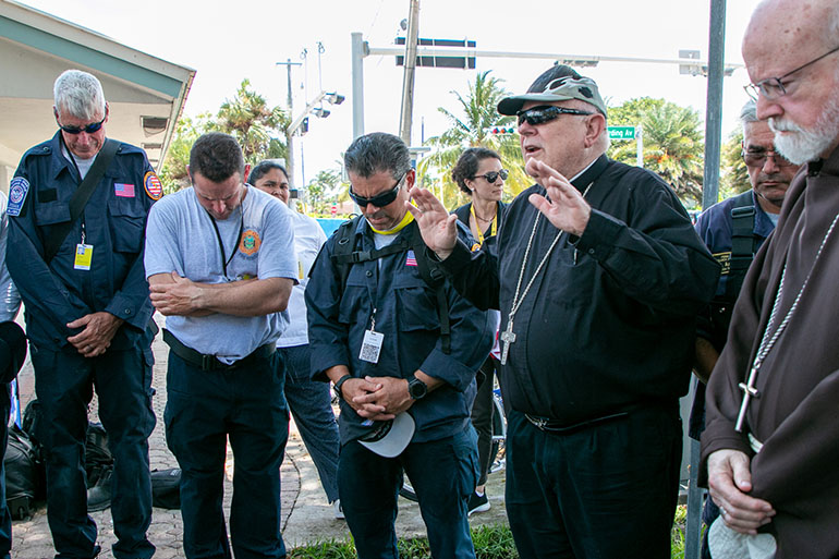 Archbishop Thomas Wenski blesses search and rescue personnel after arriving at the site of the collapsed Champlain Towers South the afternoon of July 2, 2021 with Boston Cardinal Sean O'Malley. The archbishop and cardinal prayed at and blessed the site while also visiting, praying with and blessing the search and rescue crews who have been working 24/7 since the collapse.