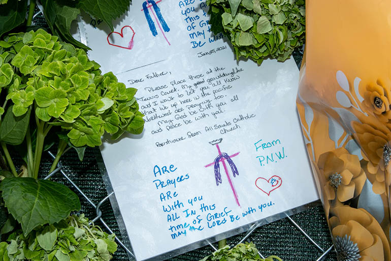 Visible at the Surfside Wall of Hope Memorial: a card written by the granddaughter of a Catholic parishioner from the state of Washington assuring "we are praying" for all those suffering due to the partial collapse of Champlain Towers South. The card was mailed to St. Joseph Parish with the specific instruction that it be placed on the memorial wall. “The only thing that they will ever remember is that you are present for them,” said Martha Lohrstorfer, a Red Cross volunteer who is among a number of chaplains —priests, rabbis, deacons and lay people — trying to console those affected by the tragedy.