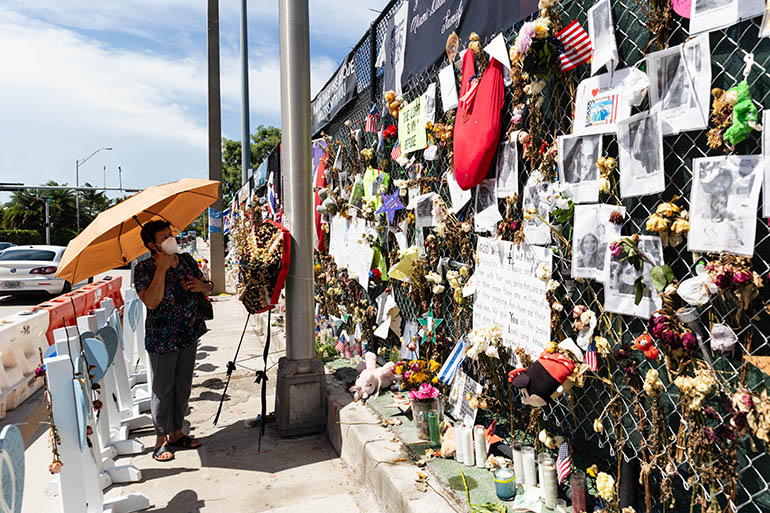 A woman looks at the ever-evolving "wall of remembrance" that commemorates the lives of the 97 victims identified so far in the June 24, 2021 tragedy.